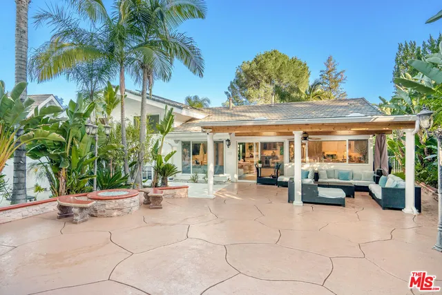 a view of a patio with table and chairs potted plants and palm tree