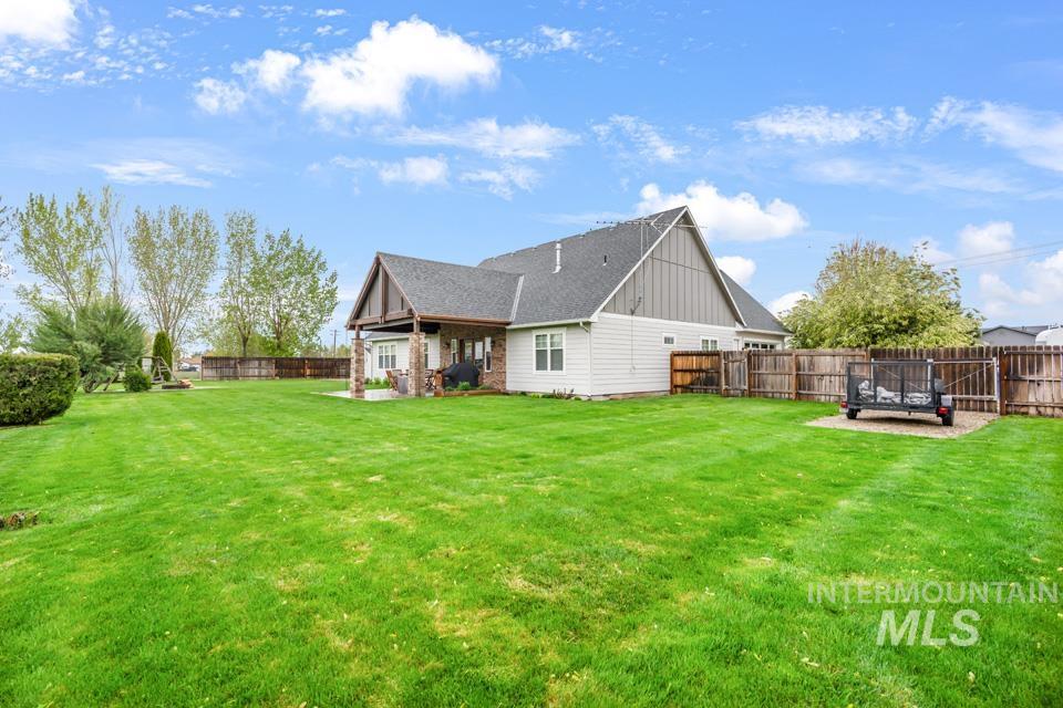 8271 Washoe Road Fruitland, ID 83619 - Photo 6 of 29 Expansive fenced backyard featuring a covered patio with brick columns, a gable roofline, and a generous lawn