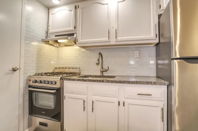 a kitchen with granite countertop a sink stove and cabinets