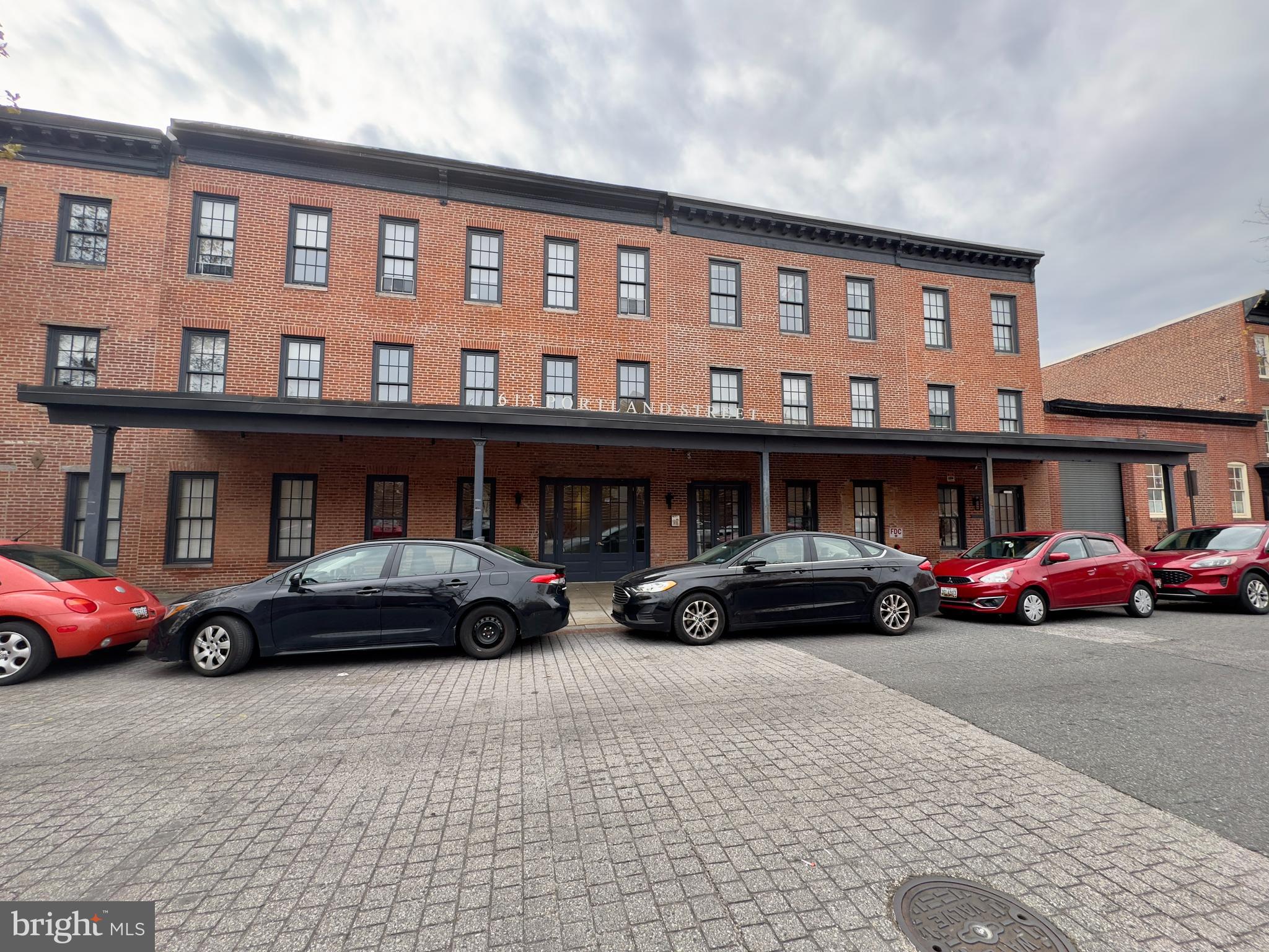 613 Portland Street, Unit 17 Baltimore, MD 21230 - Photo 1 of 12 a black car parked in front of a brick building