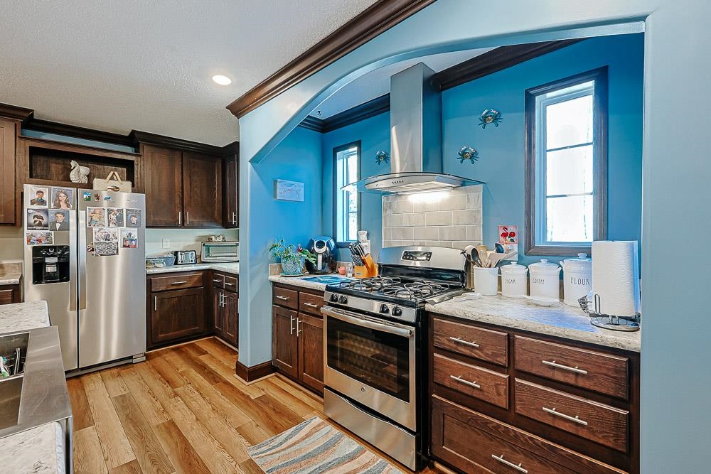 6773 Hampton Road Conway, SC 29527 - Photo 6 of 39 Kitchen with appliances with stainless steel finishes, dark brown cabinetry, ventilation hood, LVP flooring, and decorative backsplash