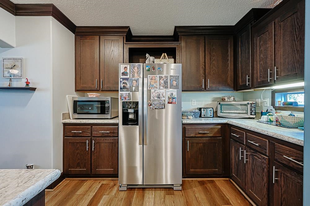 6773 Hampton Road Conway, SC 29527 - Photo 7 of 39 Kitchen with stainless steel appliances, dark brown cabinets, a textured ceiling, LVP flooring, and crown molding