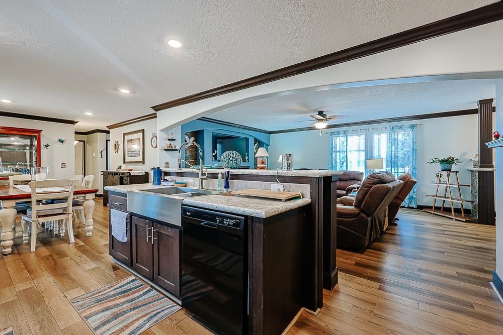 6773 Hampton Road Conway, SC 29527 - Photo 39 of 39 Kitchen featuring dark brown cabinetry, open floor plan, crown molding, an island with sink, and dishwasher