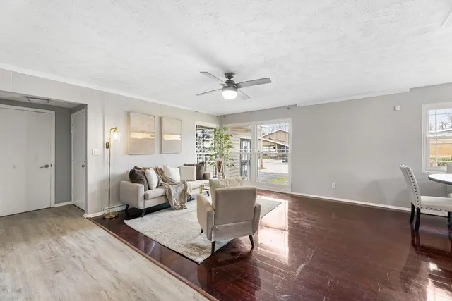 a living room with furniture a large window and wooden floor