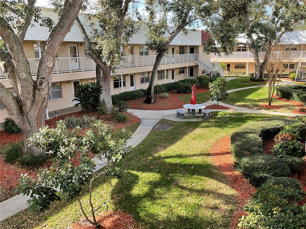 10036 63rd Avenue North, Unit 16 St. Petersburg, FL 33708 - Photo 2 of 30 a view of a white house with a big yard and potted plants and large trees