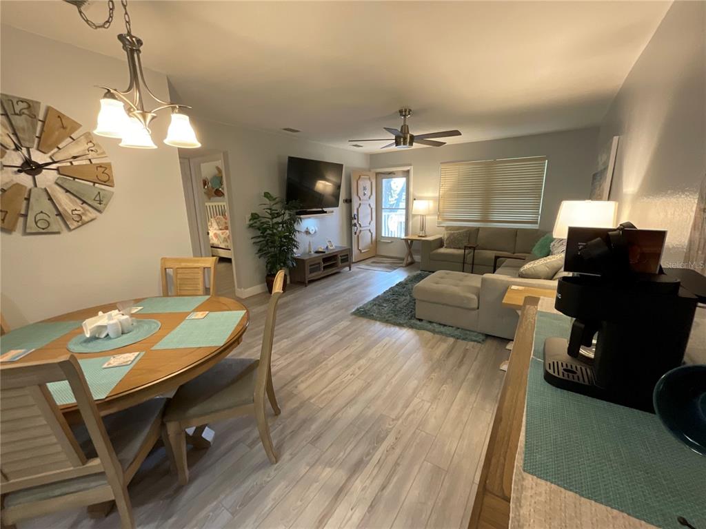 10036 63rd Avenue North, Unit 16 St. Petersburg, FL 33708 - Photo 6 of 30 a living room with furniture a chandelier a fireplace and a flat screen tv