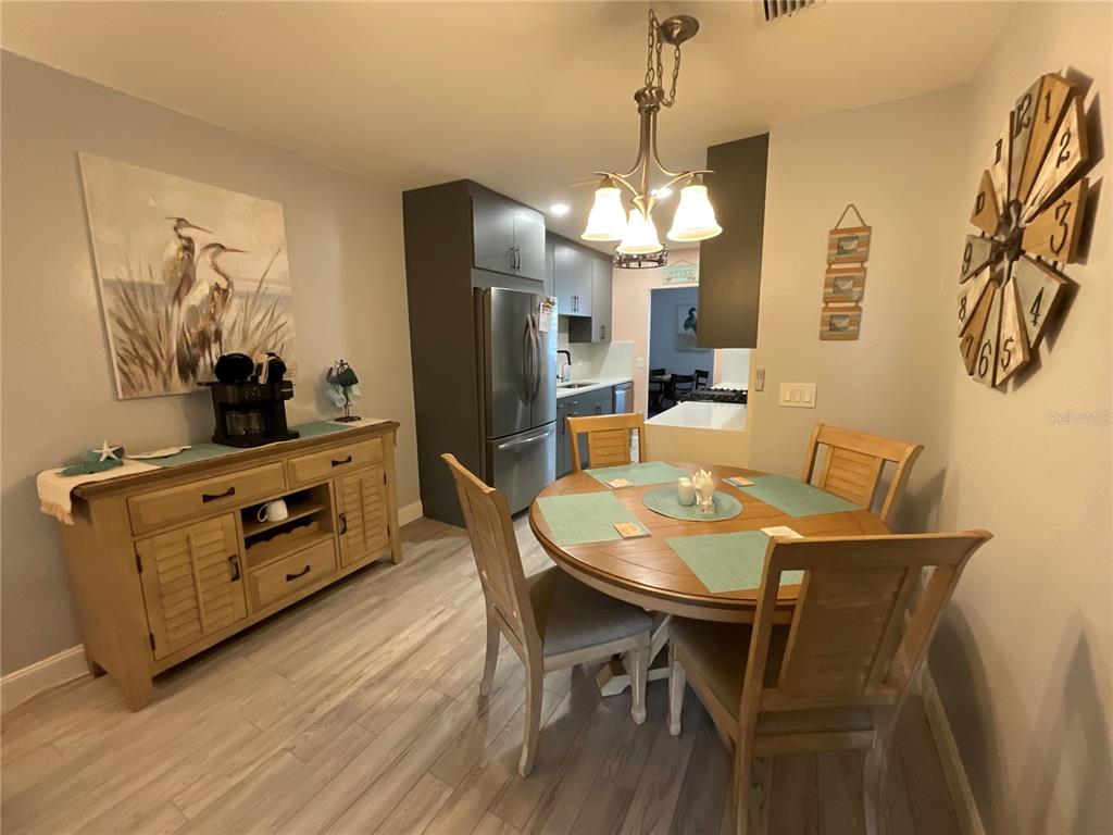 10036 63rd Avenue North, Unit 16 St. Petersburg, FL 33708 - Photo 9 of 30 a dining room with furniture a chandelier and wooden floor