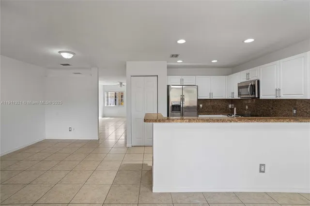 a kitchen with stainless steel appliances granite countertop a refrigerator and a stove top oven