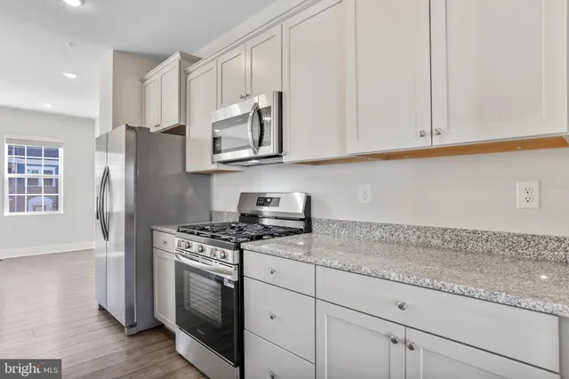 a kitchen with granite countertop white cabinets and stainless steel appliances