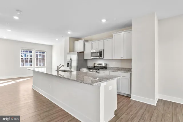 a kitchen with stainless steel appliances granite countertop a sink a stove a refrigerator and cabinets