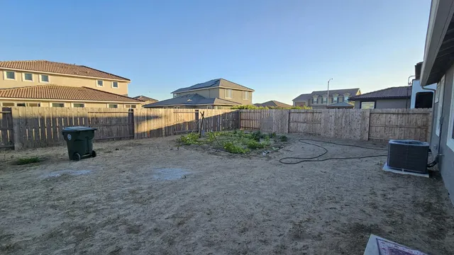 a view of a blue house with yard and a wooden fence