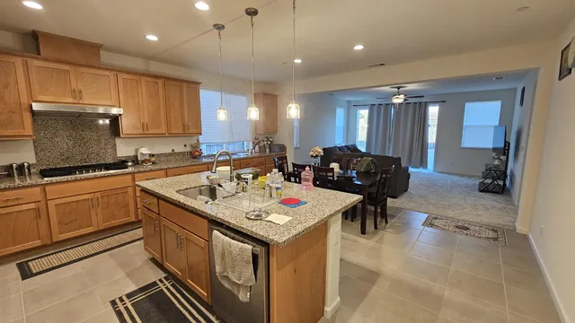 a kitchen with stainless steel appliances granite countertop a sink counter space cabinets and a view of living room