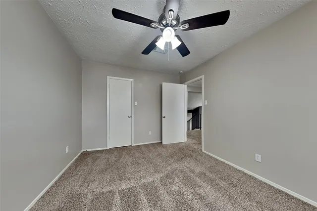 an empty room with chandelier fan and windows
