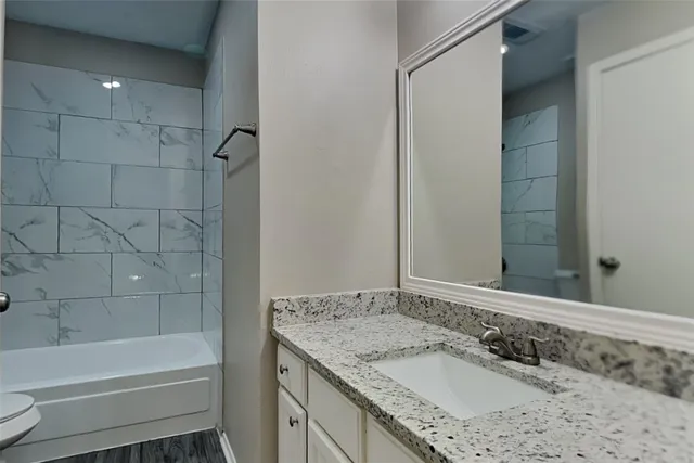 a bathroom with a granite countertop sink a toilet and bathtub
