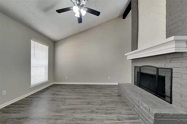 an empty room with windows and fireplace