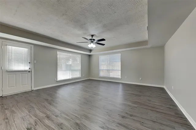 a view of an empty room with a window and wooden floor