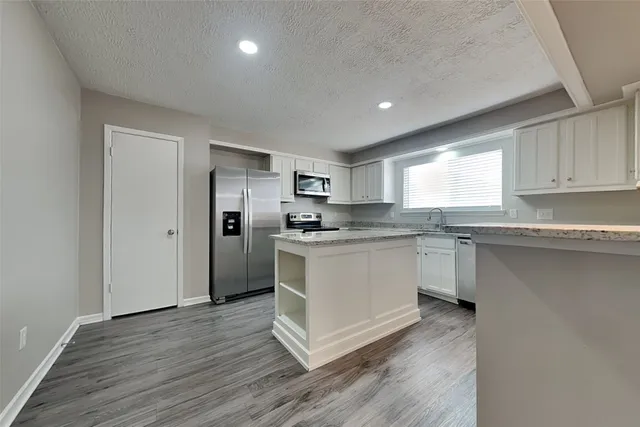 a kitchen with granite countertop white cabinets and white appliances