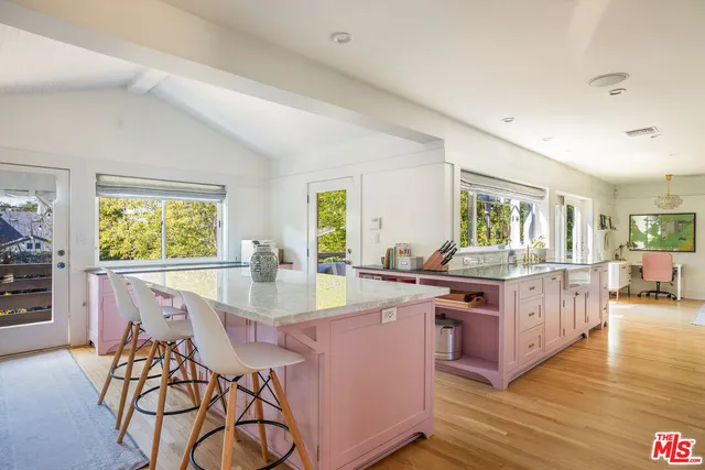 a kitchen with stainless steel appliances granite countertop a stove top oven a dining table and chairs with wooden floor