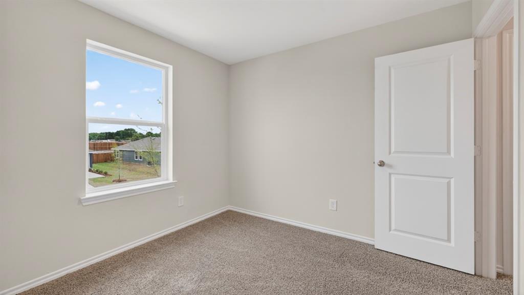 3534 Spring Time Street Forney, TX 75126 - Photo 21 of 24 Room featuring a large window, light gray wall paint, white trim, gray carpet flooring, and a white two-panel interior door with brushed nickel hardware