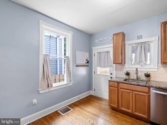 a kitchen with stainless steel appliances granite countertop wooden floors a sink and a window