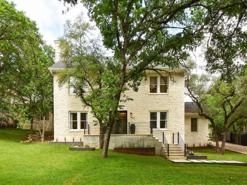 a view of a white house with a big yard and large trees