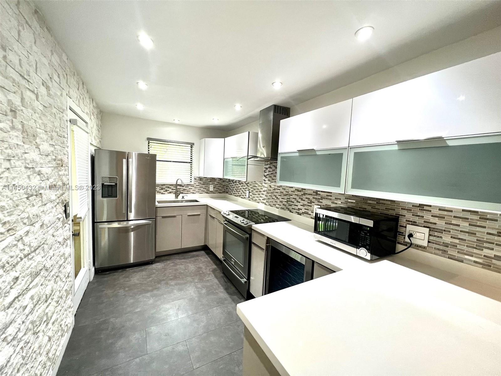 15661 Southwest 104th Terrace, Unit 321 Miami, FL 33196 - Photo 9 of 21 a kitchen that has a lot of white cabinets a sink and stainless steel appliances