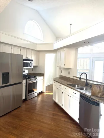 a kitchen with granite countertop a sink stove and refrigerator