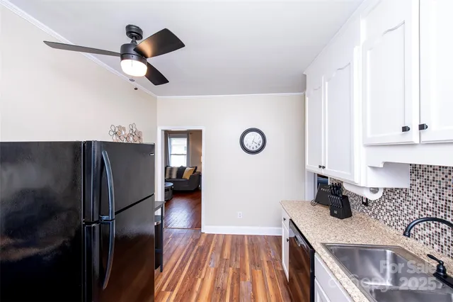 a kitchen with stainless steel appliances granite countertop a refrigerator a sink dishwasher a stove and white countertops with wooden floor