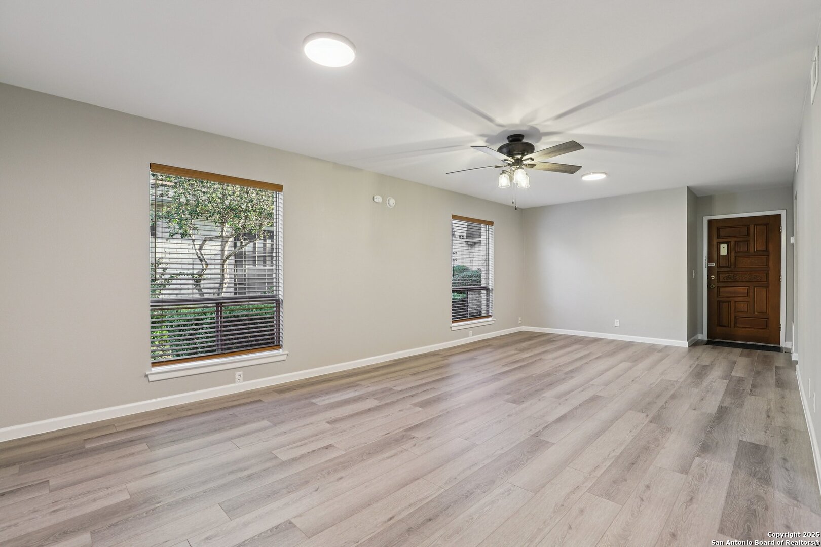 3441 Turtle Village Drive, Unit 92FF San Antonio, TX 78230 - Photo 6 of 34 an empty room with wooden floor chandelier fan and windows