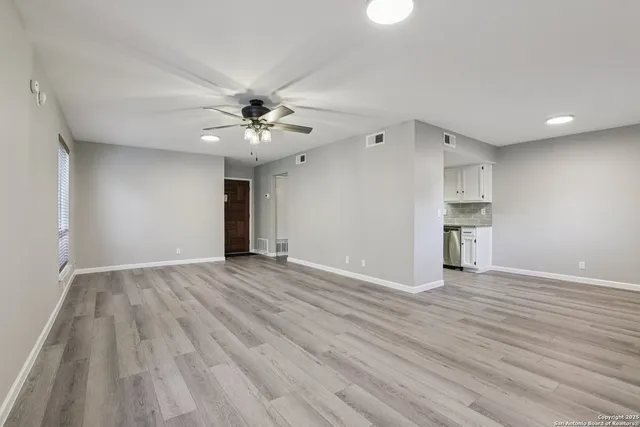 an empty room with wooden floor and a ceiling fan