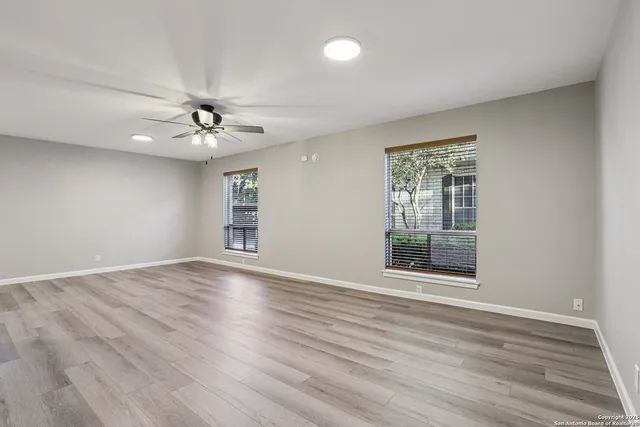 a view of an empty room with a window and wooden floor