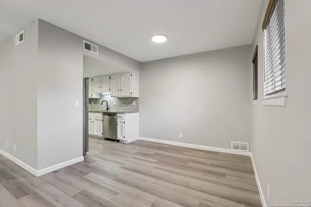a view of kitchen and empty room with wooden floor
