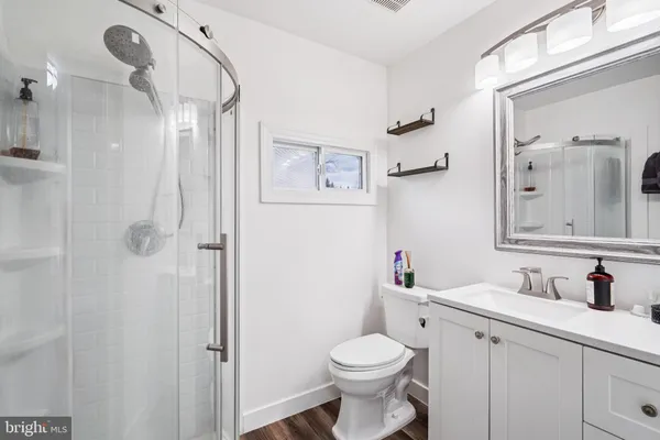 a bathroom with a toilet sink vanity granite and shower