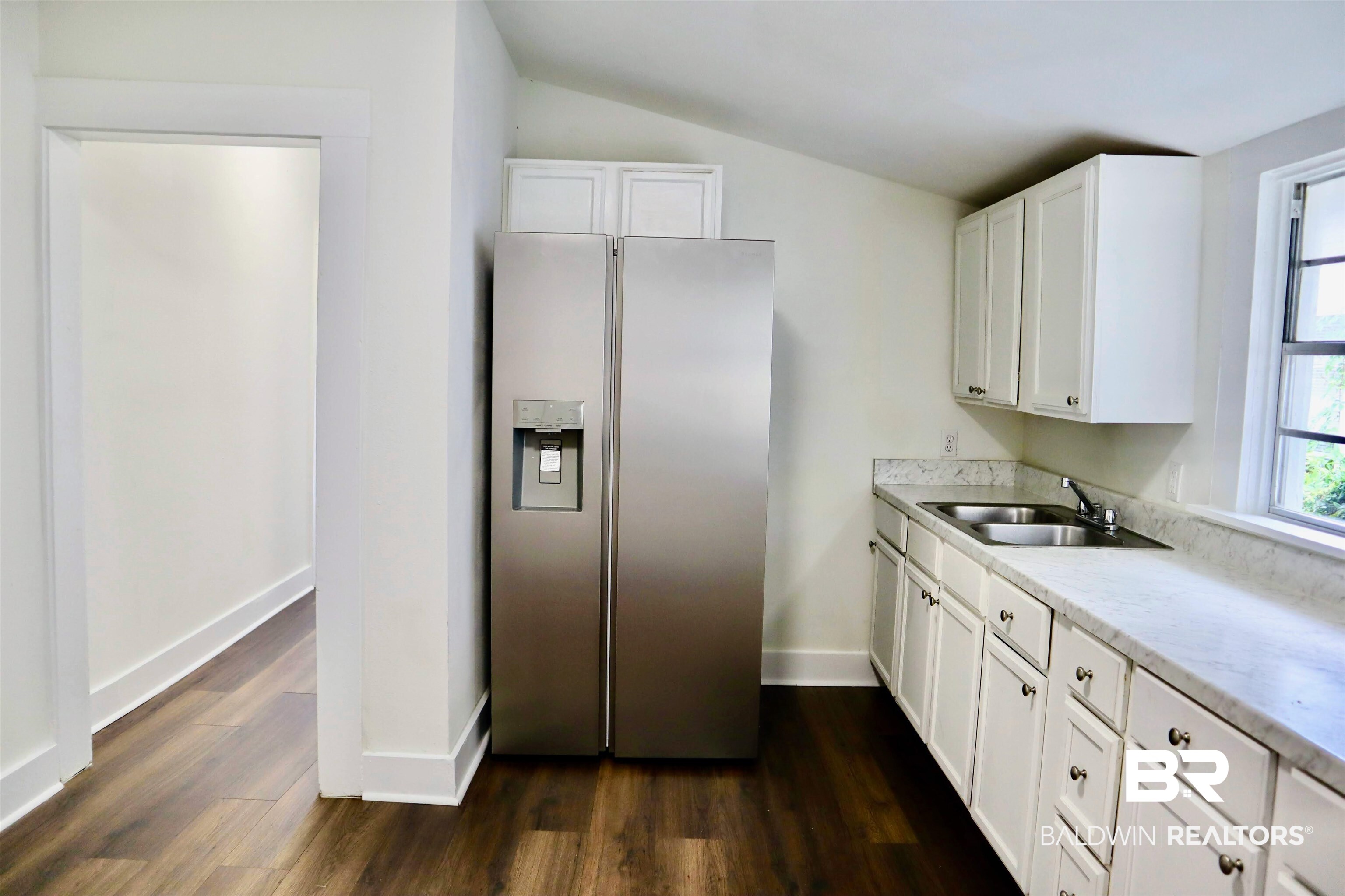 1009 Baltimore Street Mobile, AL 36605 - Photo 14 of 17 Kitchen with stainless steel fridge with ice dispenser, lofted ceiling, dark wood-style flooring, and white cabinetry