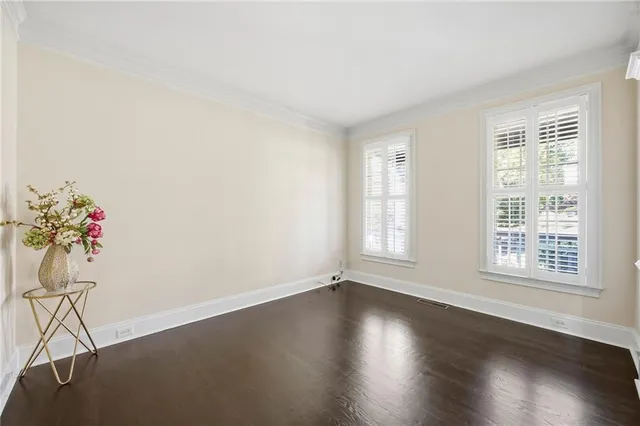 a view of an empty room with wooden floor and a potted plant