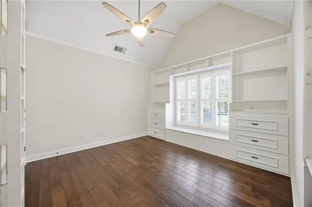 a view of empty room with wooden floor and ceiling fan