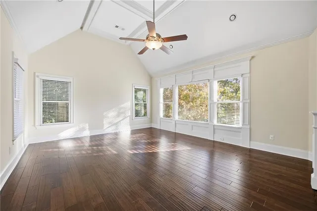 an empty room with wooden floor fan and windows
