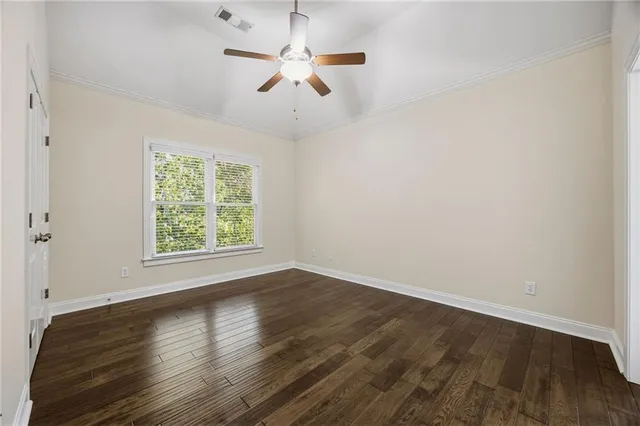 an empty room with wooden floor fan and windows