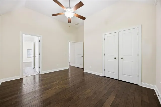 an empty room with wooden floor and a ceiling fan