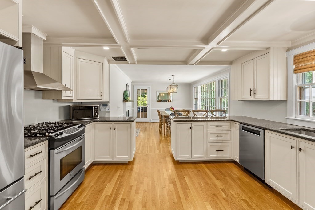 49 Sears Road Wayland, MA 01778 - Photo 8 of 30 a kitchen with granite countertop a stove top oven a sink dishwasher and white cabinets with wooden floor