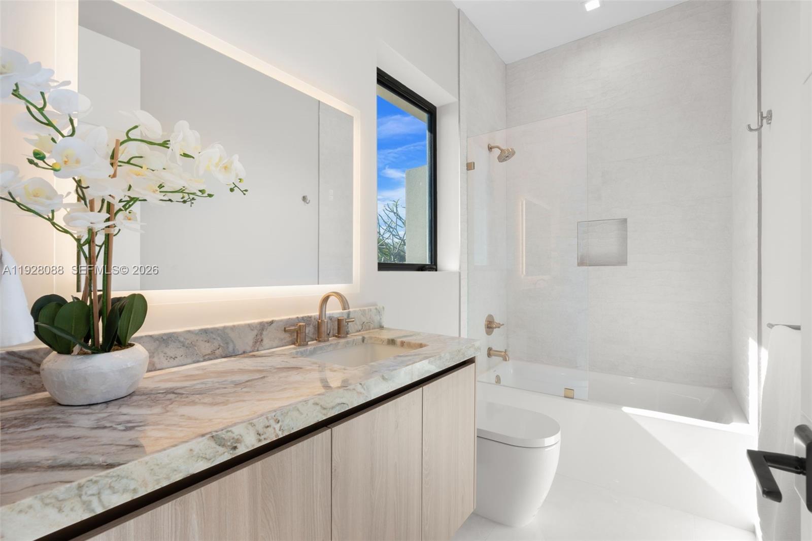 4910 Northeast 27th Avenue Lighthouse Point, FL 33064 - Photo 50 of 68 a bathroom with a granite countertop sink a toilet and a bathtub