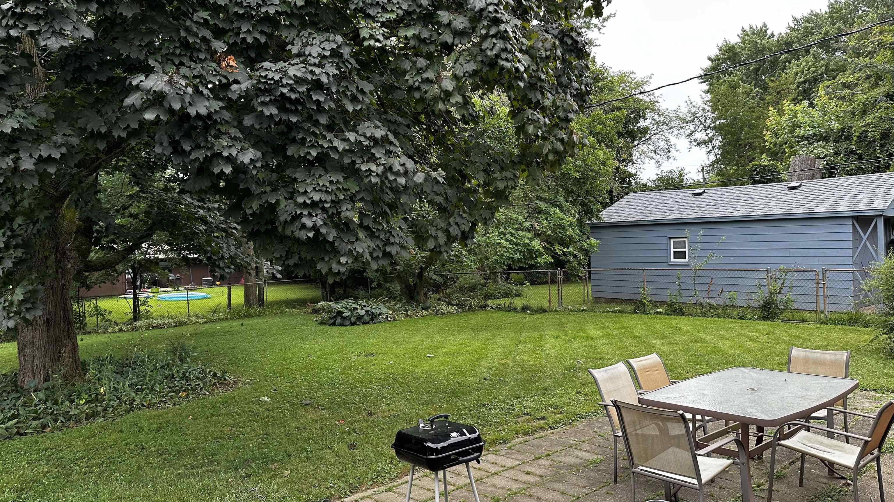 4721 Highcrest Road Rockford, IL 61107 - Photo 18 of 22 a view of a backyard with table and chairs potted plants and a large tree