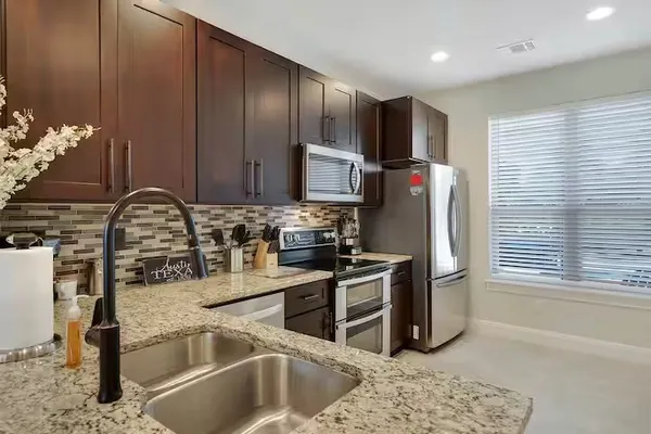 a kitchen with stainless steel appliances granite countertop a sink stove and refrigerator