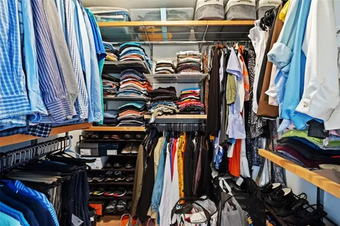 a view of walk in closet with clothes and shoes