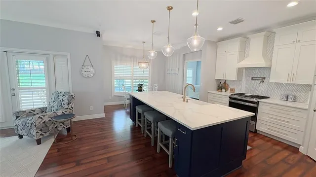 a kitchen with kitchen island a island wooden floors stove and white cabinets