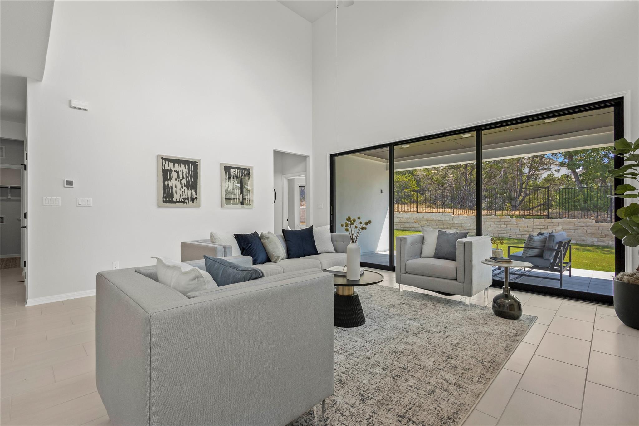1128 Villa Rialto View Leander, TX 78641 - Photo 21 of 40 A living area with soaring ceilings and large glass doors connecting to a serene outdoor space.