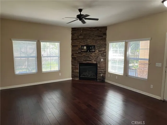 an empty room with wooden floor fireplace and windows