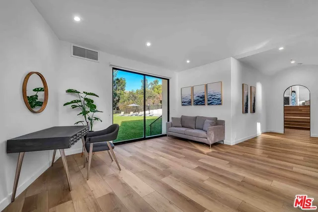 a living room with furniture a rug potted plant and a large window