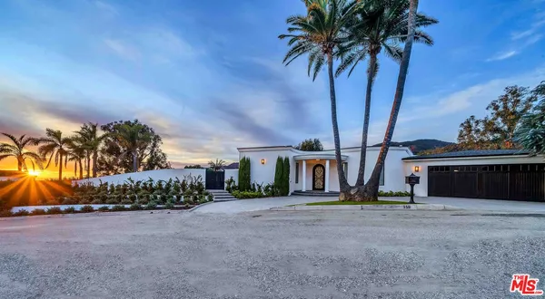 front view of a house with a yard and palm trees