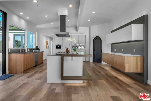 a large kitchen with stainless steel appliances a large counter top a stove and a refrigerator